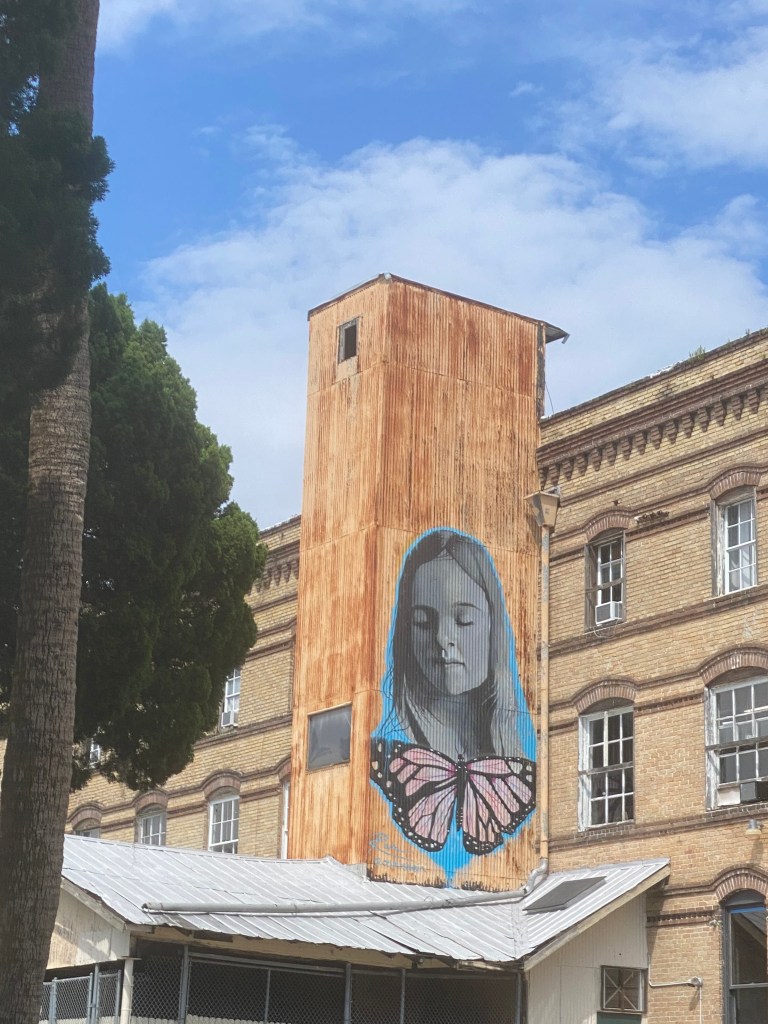 A wall mural of a girl with blonde hair and pink butterfly in West Tampa, Florida.