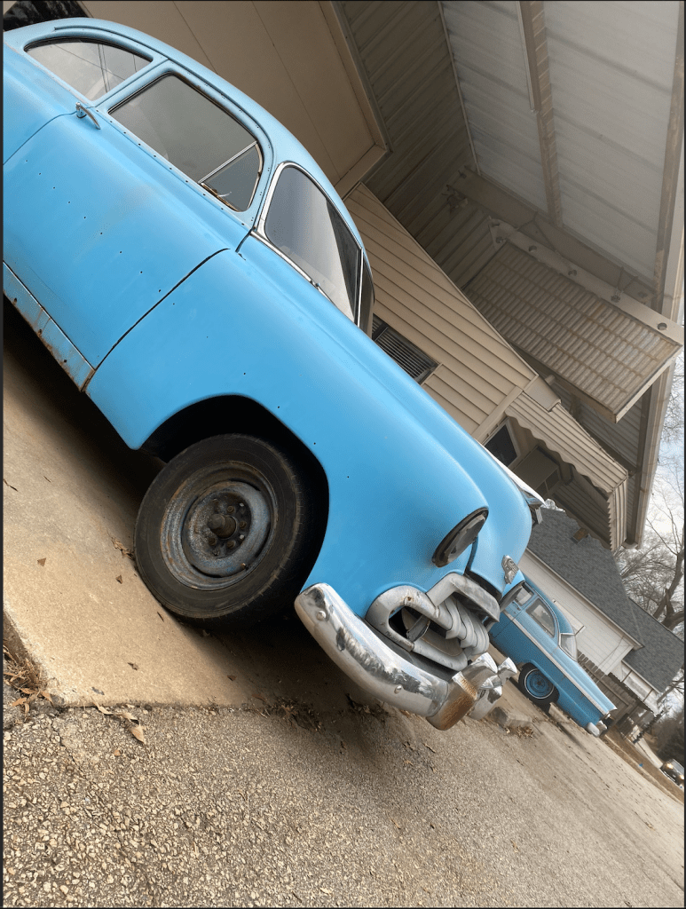 Two old-style blue cars positioned on a diagonal.